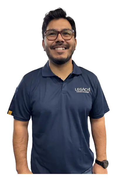 Jay, owner of Legacy Barbershop Sensory Friendly, smiling in glasses and a navy Legacy polo shirt